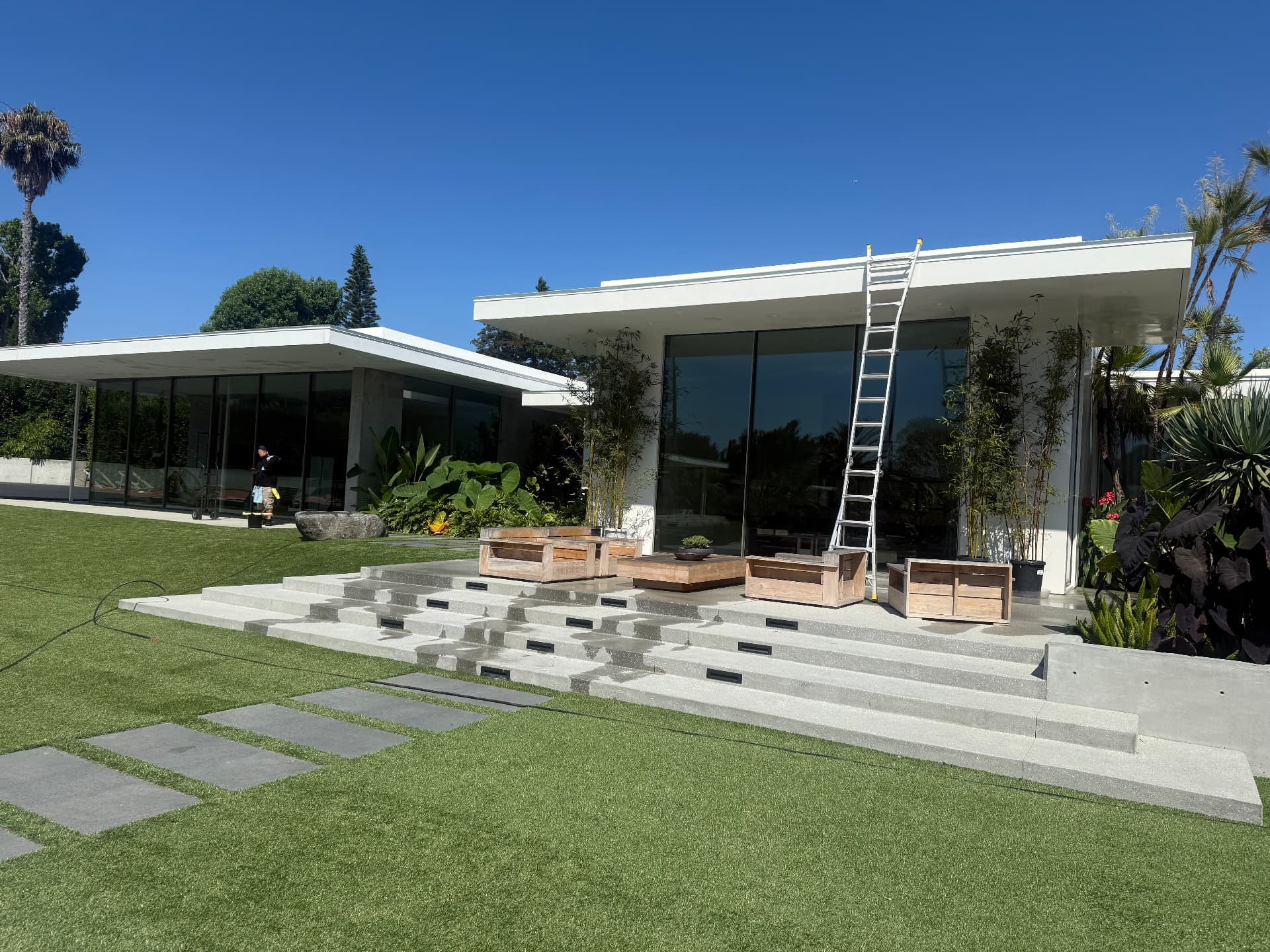 Technician cleaning floor-to-ceiling glass on a modern home