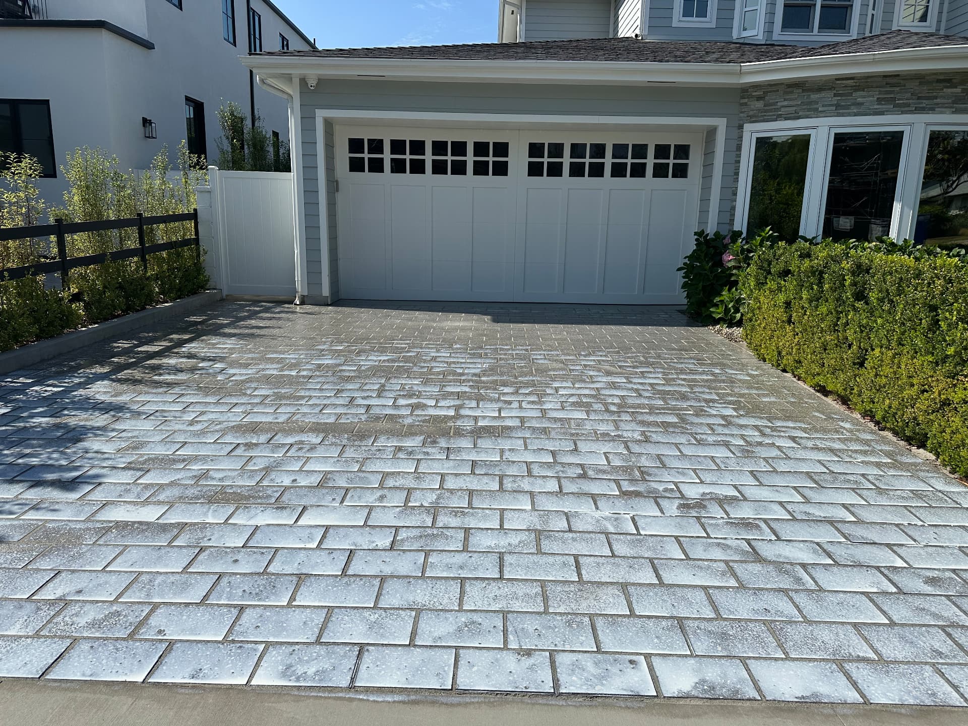 Freshly sealed paver driveway in front of a modern home