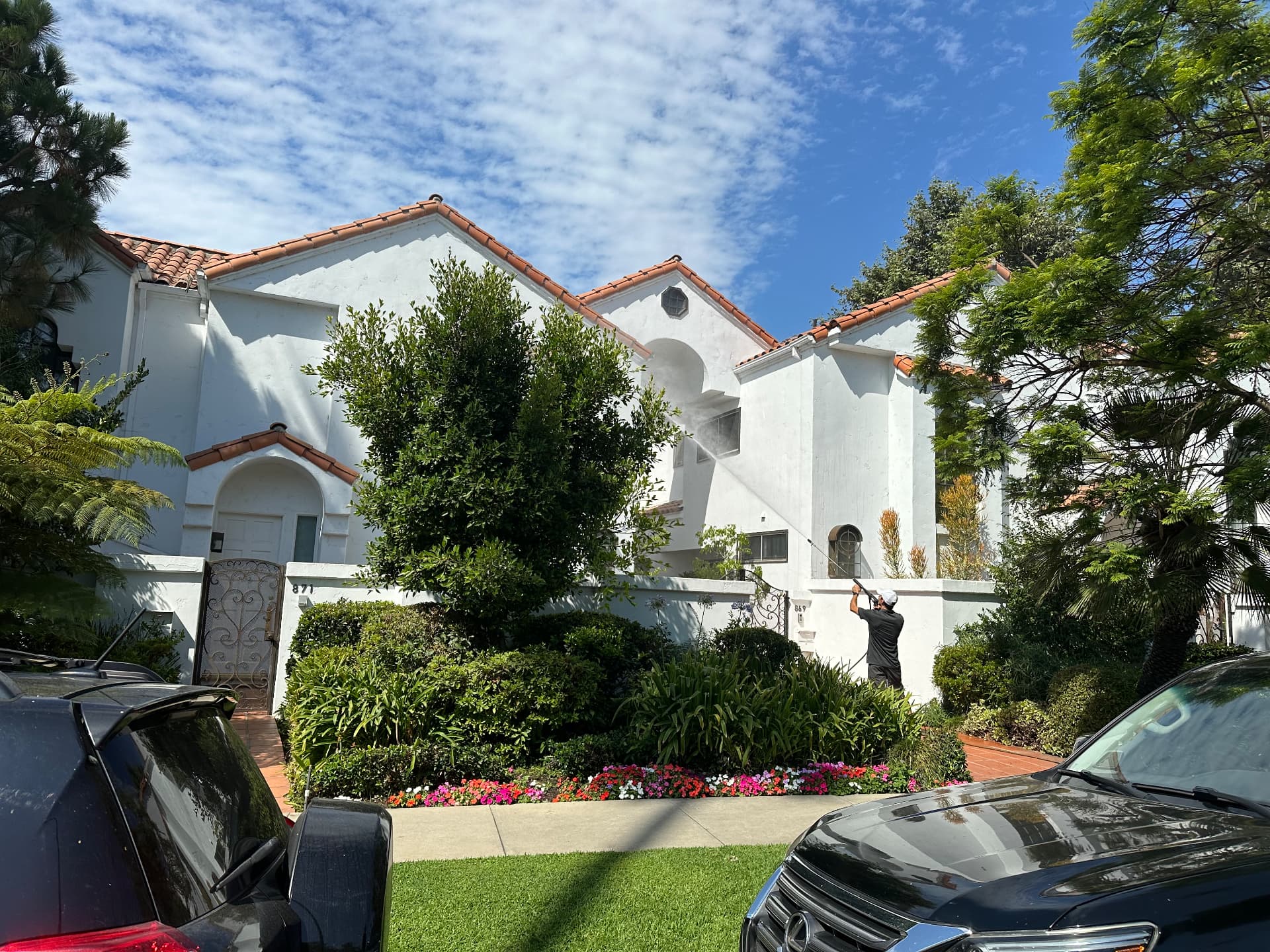 Technician soft washing the white stucco exterior of a home