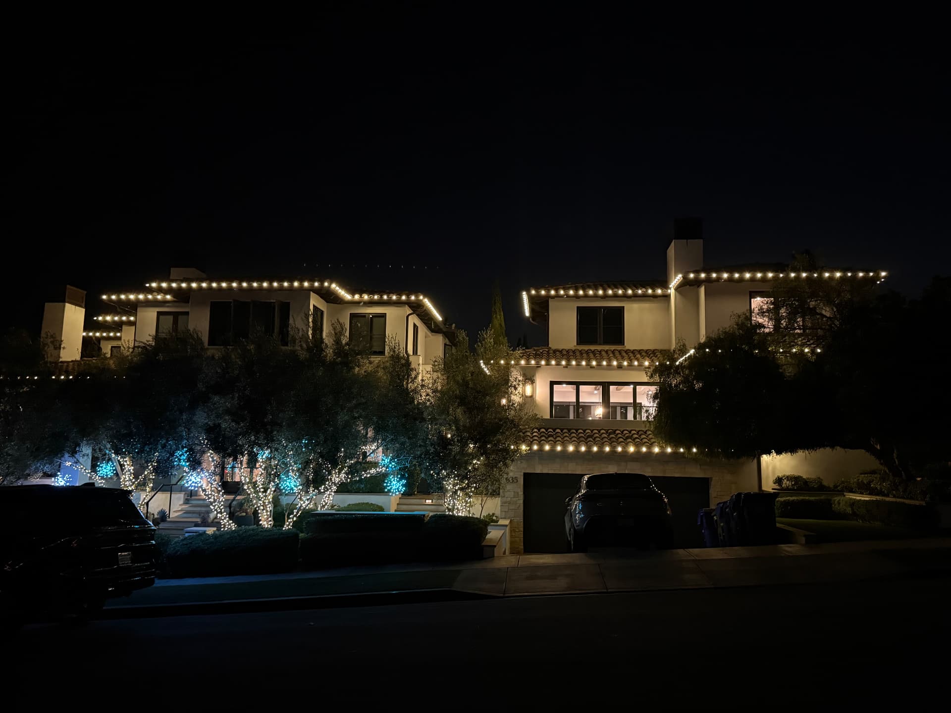 Luxury home at night with warm white roofline holiday lighting